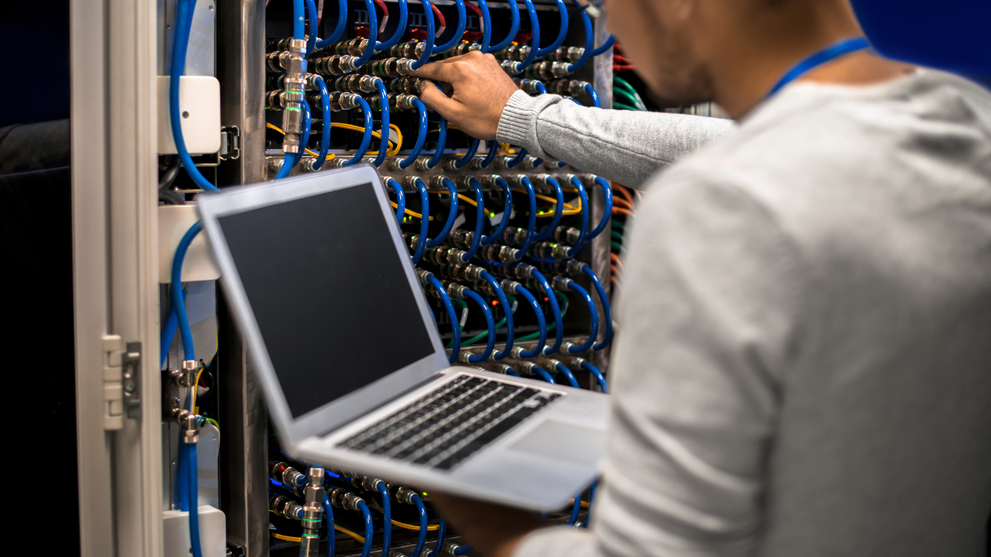A network engineer configuring network cables and hardware in a server room.