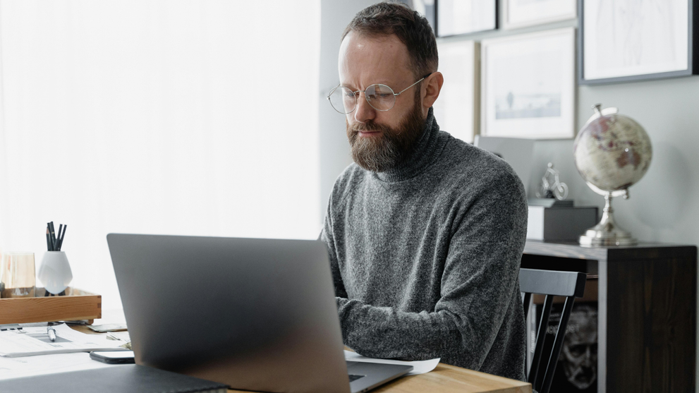 Man studying for CompTIA A+ exams on a silver laptop.