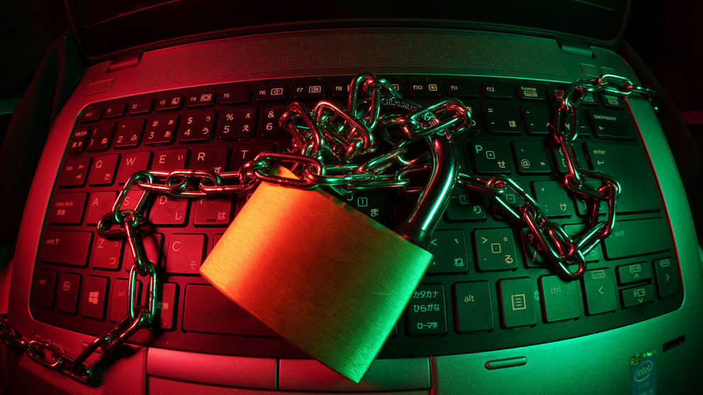 Metal lock wrapped in chains resting on a laptop keyboard.