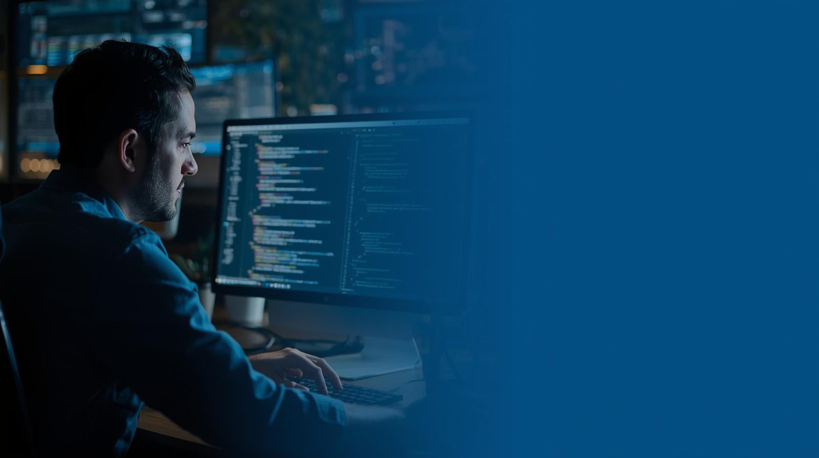Person working on a computer with code displayed in a dark room